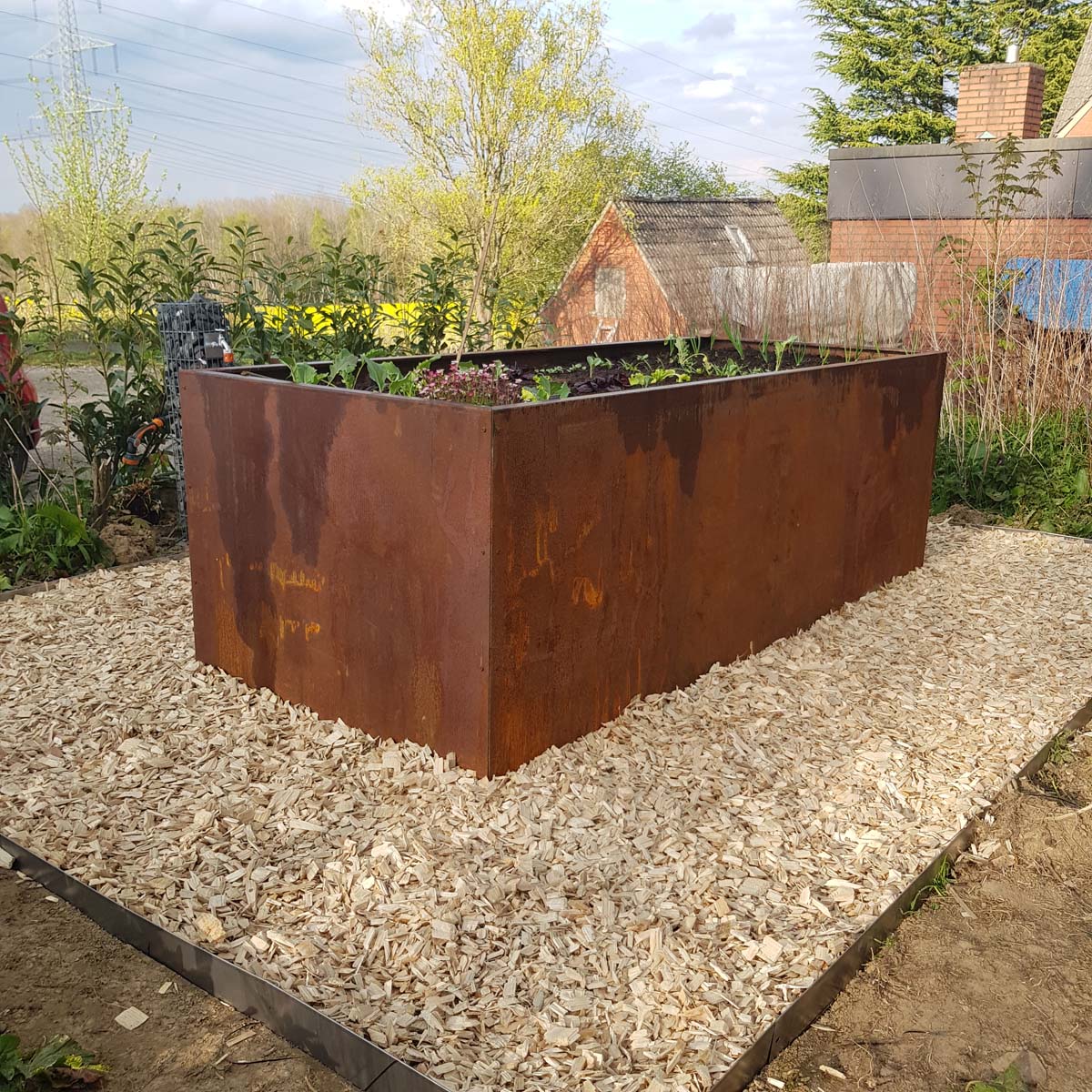 Ein Hochbeet aus Edelrost, das auf einer großen freien Fläche im Garten steht